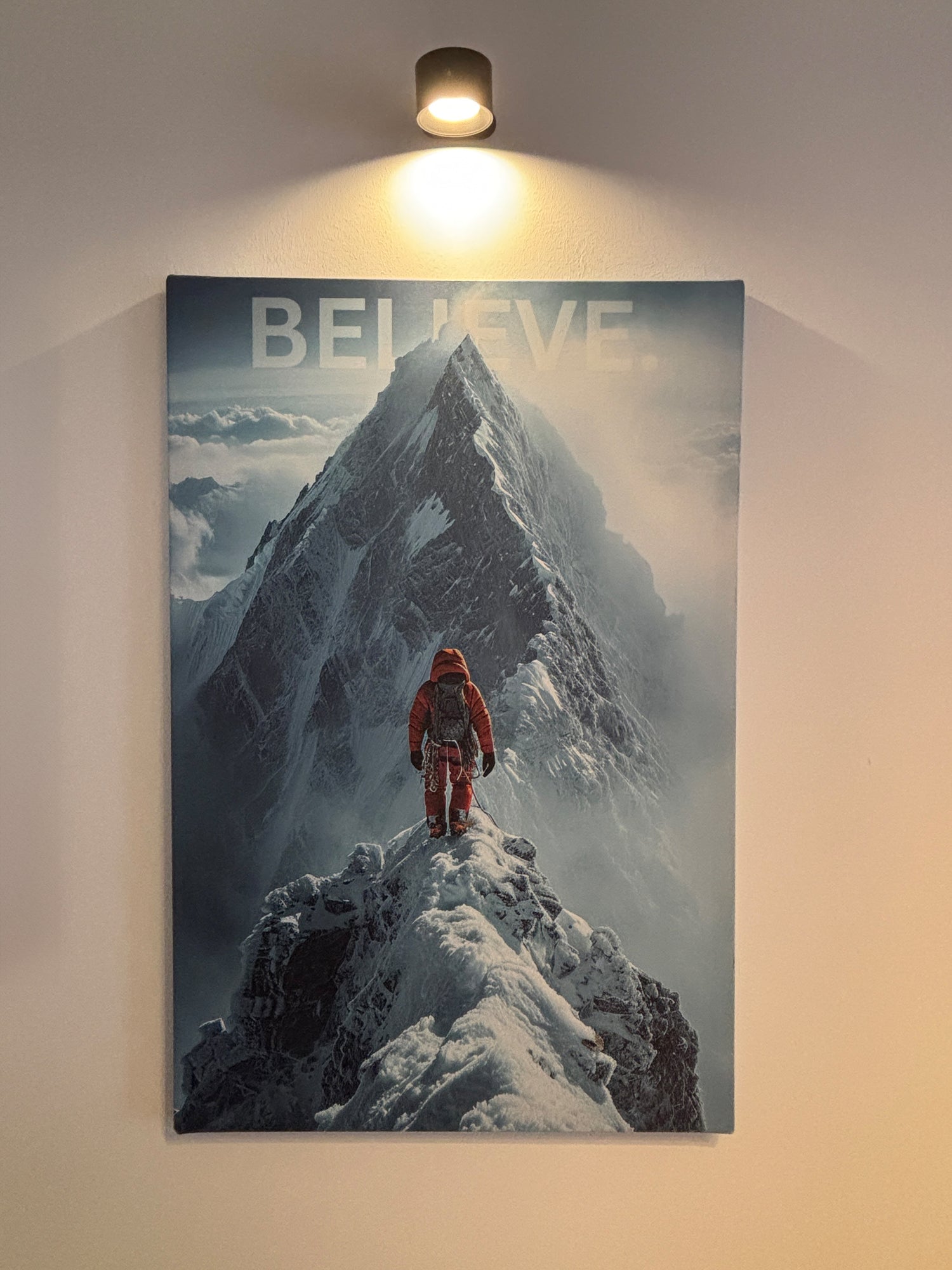 Leinwand mit einem Bergsteiger der vor einem großen Berg steht im Hintergrund ein Wort "Believe"