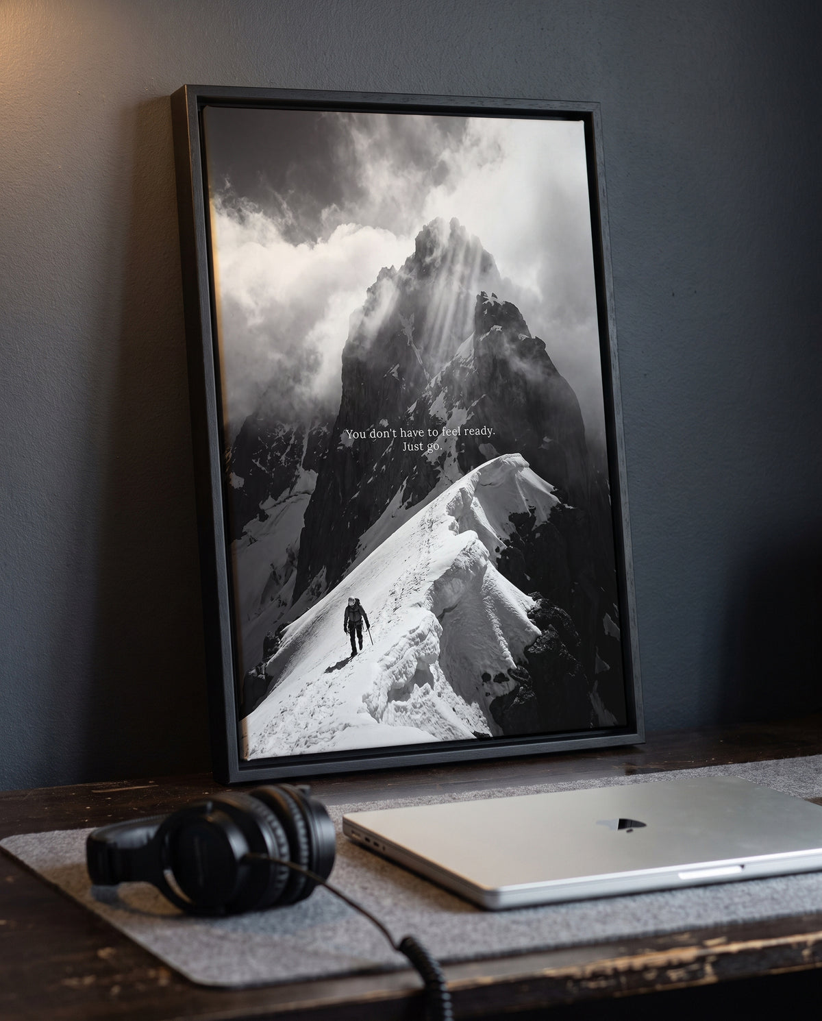 Bergsteiger Motivationsposter Just Go über einem Schreibtisch mit Laptop